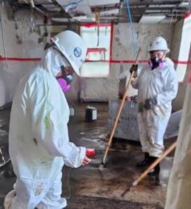 Hazardous Material abatement crew performing work activities and reading monitor results